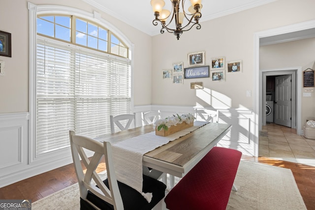 dining room with a chandelier, ornamental molding, washer / dryer, and hardwood / wood-style flooring