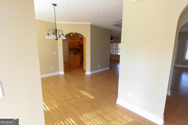 unfurnished room with ornamental molding, hardwood / wood-style floors, a textured ceiling, and a notable chandelier