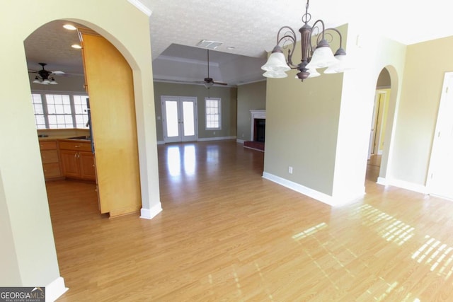 unfurnished dining area featuring ceiling fan with notable chandelier, a textured ceiling, and light wood-type flooring