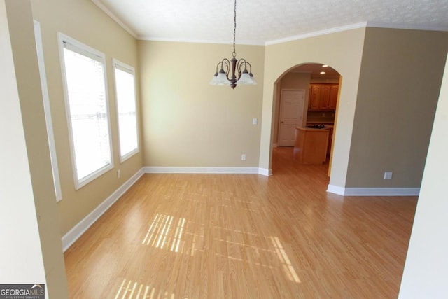 empty room featuring crown molding, a notable chandelier, a textured ceiling, and light hardwood / wood-style flooring