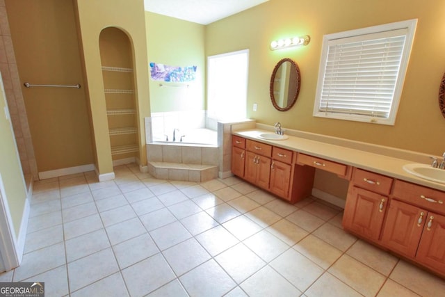 bathroom featuring vanity, a relaxing tiled tub, and tile patterned floors