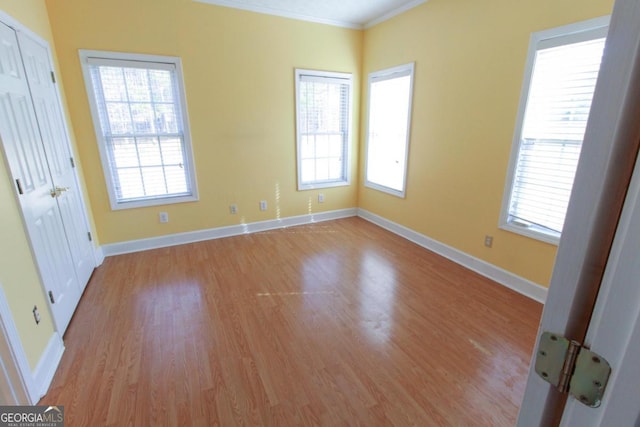 spare room with ornamental molding and light hardwood / wood-style flooring