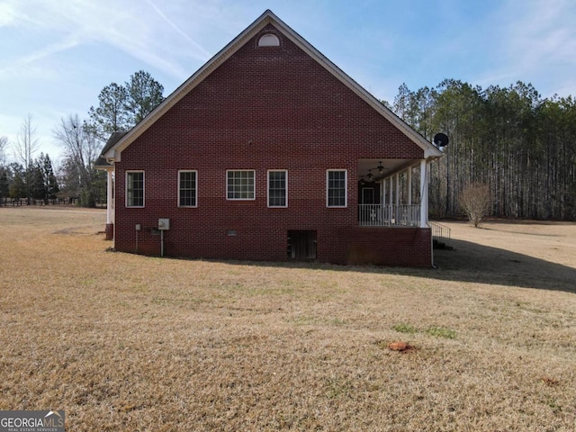 view of side of home with ceiling fan and a lawn