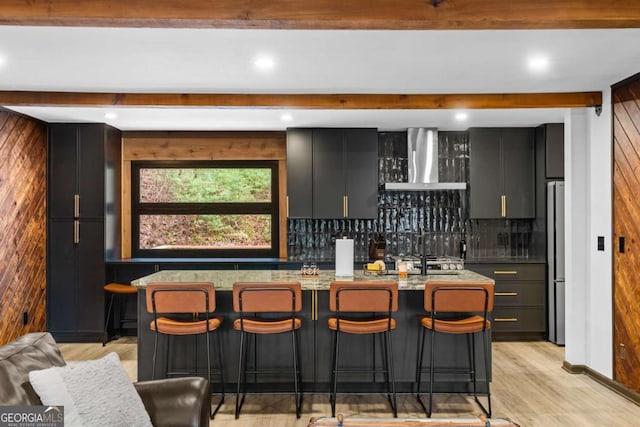 bar with tasteful backsplash, wall chimney exhaust hood, freestanding refrigerator, beam ceiling, and indoor wet bar