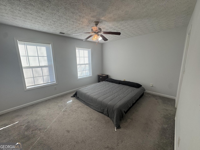 carpeted bedroom with ceiling fan and a textured ceiling