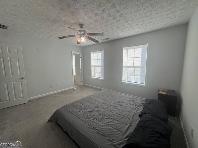 bedroom with ceiling fan, light colored carpet, and a textured ceiling