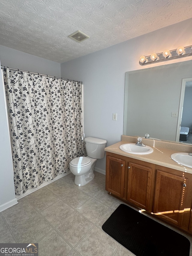 bathroom with vanity, toilet, tile patterned flooring, and a textured ceiling