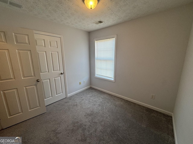 unfurnished bedroom featuring a textured ceiling and carpet