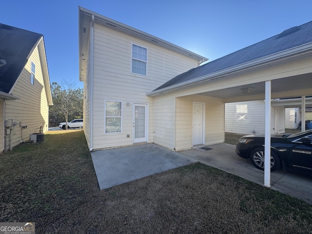 rear view of house with a carport, a yard, and central AC