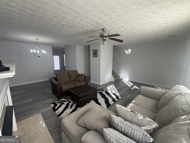 living room featuring dark wood-type flooring, ceiling fan with notable chandelier, and a textured ceiling