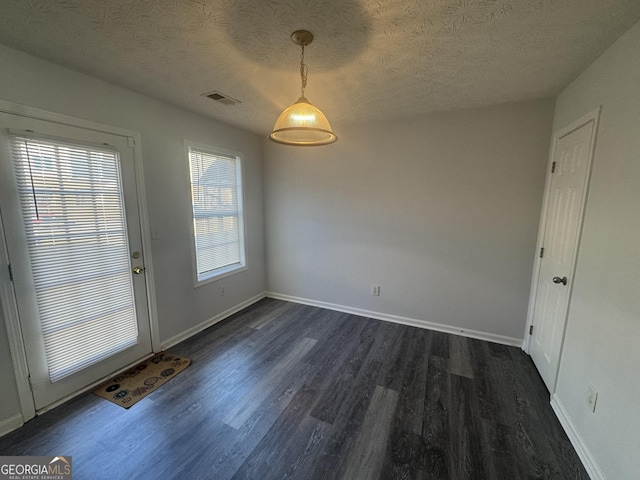 unfurnished dining area with a textured ceiling and dark hardwood / wood-style flooring