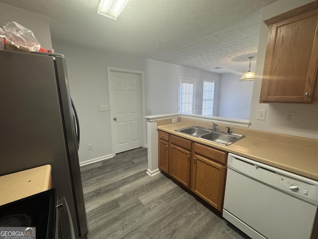 kitchen with sink, stainless steel refrigerator, white dishwasher, dark hardwood / wood-style flooring, and decorative light fixtures