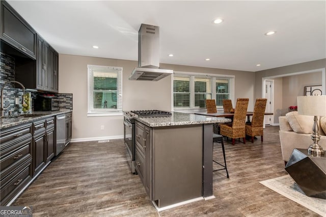 kitchen featuring sink, a breakfast bar, stainless steel appliances, dark hardwood / wood-style floors, and island exhaust hood