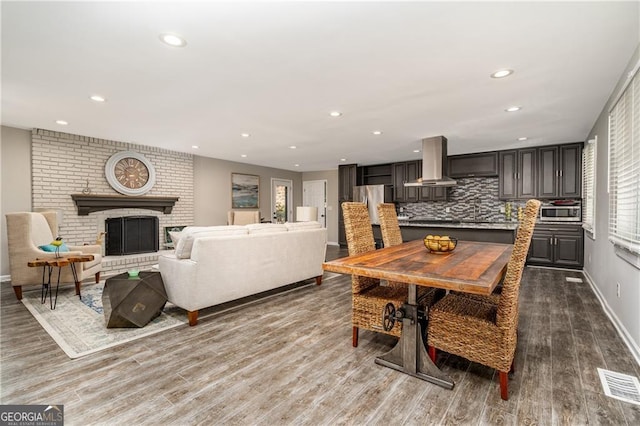 dining room featuring a brick fireplace and light wood-type flooring