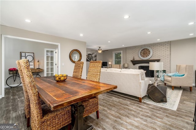 dining room featuring a fireplace, wood-type flooring, and ceiling fan