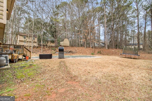 view of yard with a wooden deck and a trampoline