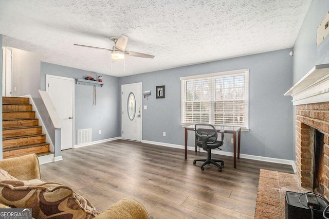 office space featuring dark hardwood / wood-style floors, a textured ceiling, a fireplace, and ceiling fan