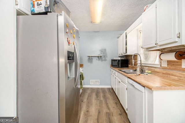 kitchen with sink, white cabinets, white dishwasher, stainless steel refrigerator with ice dispenser, and light hardwood / wood-style flooring