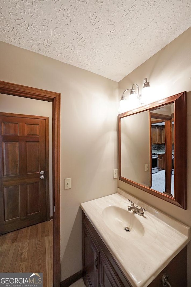 bathroom featuring vanity, wood-type flooring, and a textured ceiling