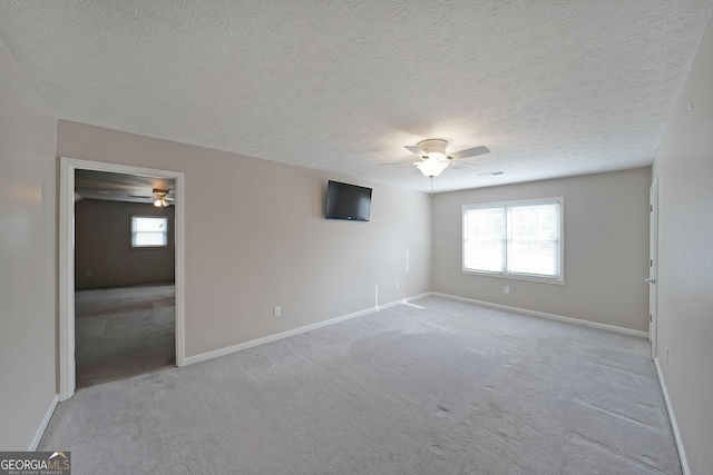 carpeted spare room with a textured ceiling and ceiling fan