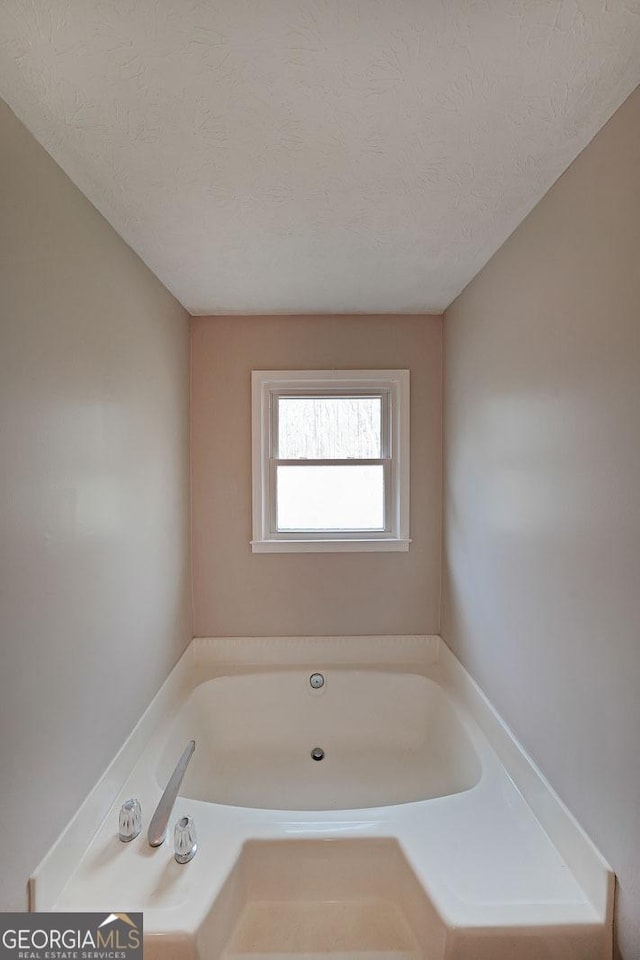 bathroom featuring a washtub and a textured ceiling