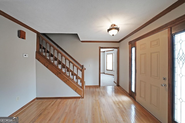 entrance foyer with crown molding, a textured ceiling, and light hardwood / wood-style floors