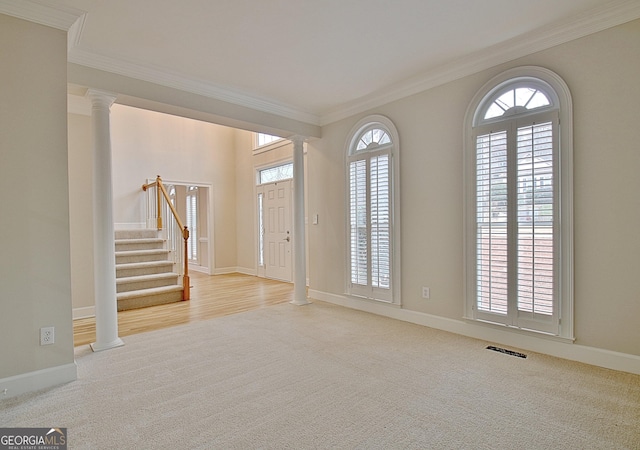 entrance foyer with light colored carpet, ornamental molding, and decorative columns