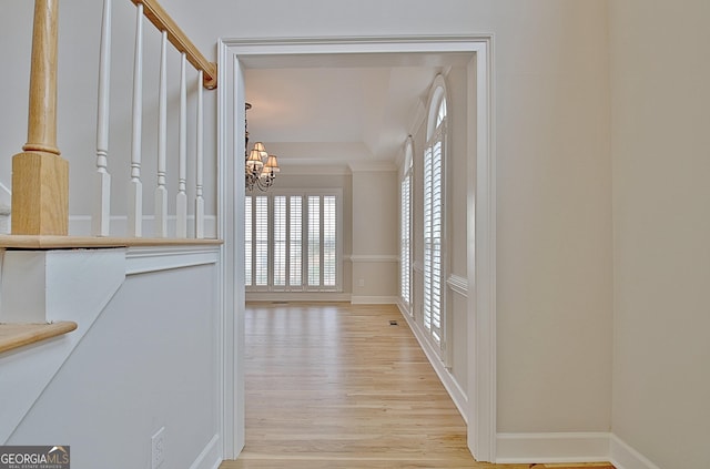 corridor with a notable chandelier and light wood-type flooring