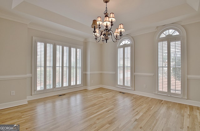 spare room with a notable chandelier, crown molding, light hardwood / wood-style floors, and a raised ceiling