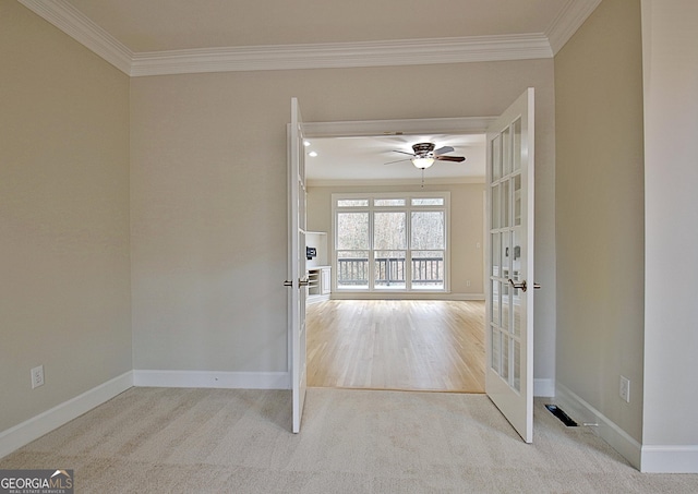 empty room with crown molding, light colored carpet, french doors, and ceiling fan