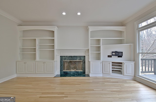 unfurnished living room featuring ornamental molding, a fireplace, and light hardwood / wood-style flooring