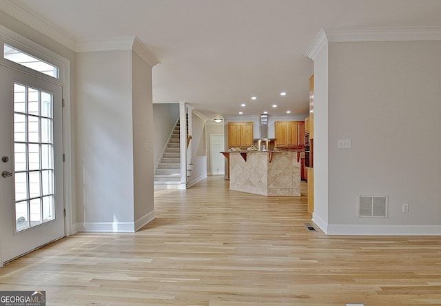 entrance foyer with crown molding and light hardwood / wood-style floors