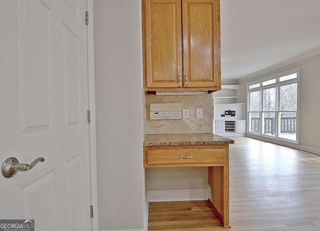 kitchen featuring tasteful backsplash, crown molding, light stone countertops, and light wood-type flooring