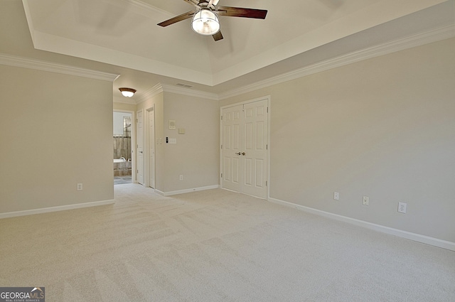 carpeted spare room featuring a raised ceiling, ornamental molding, and ceiling fan