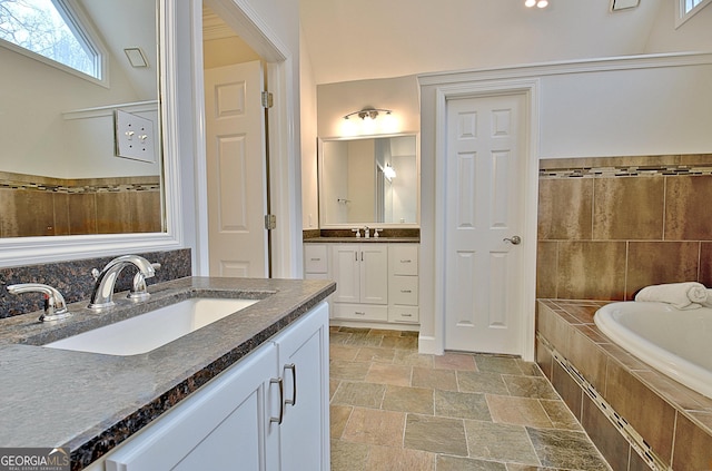 bathroom featuring vanity and a relaxing tiled tub