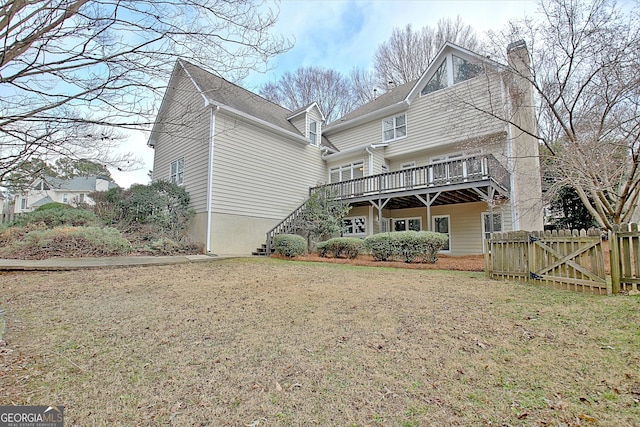 rear view of house with a wooden deck and a yard