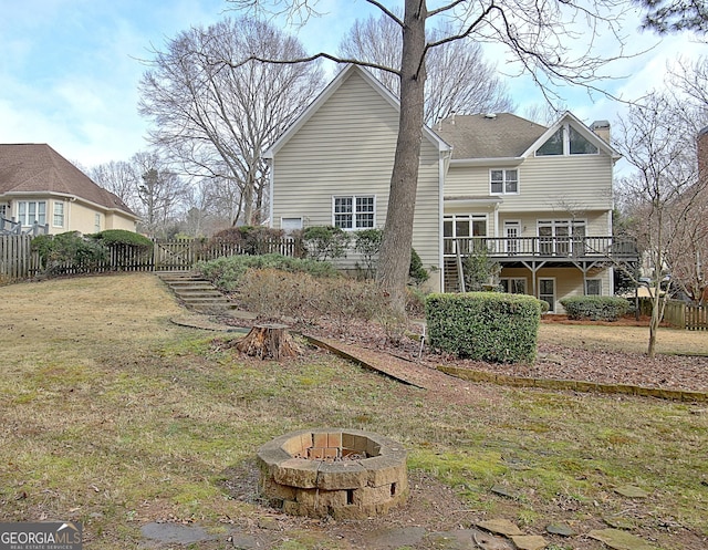 back of house featuring a wooden deck, a fire pit, and a yard