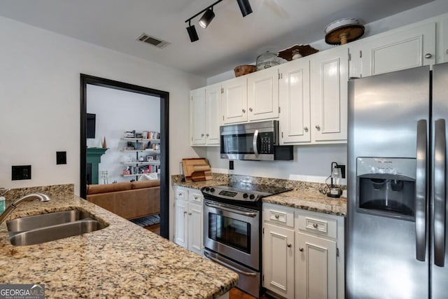 kitchen featuring white cabinetry, sink, light stone counters, stainless steel appliances, and track lighting