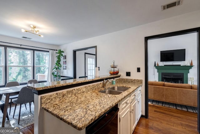 kitchen featuring dark hardwood / wood-style floors, white cabinetry, dishwasher, sink, and light stone countertops