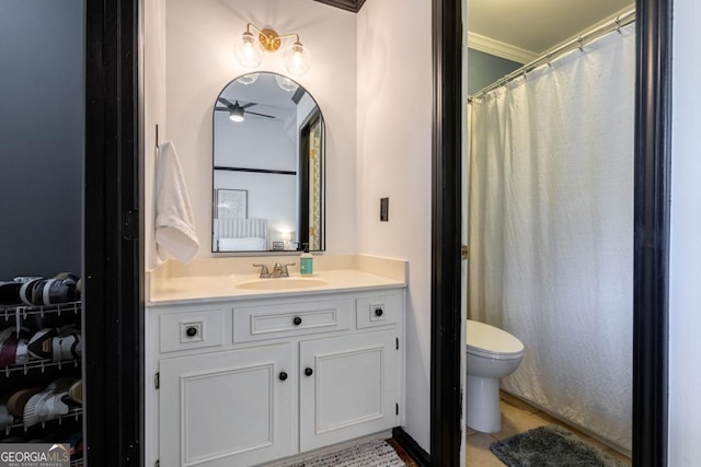 bathroom with ceiling fan, vanity, toilet, and ornamental molding