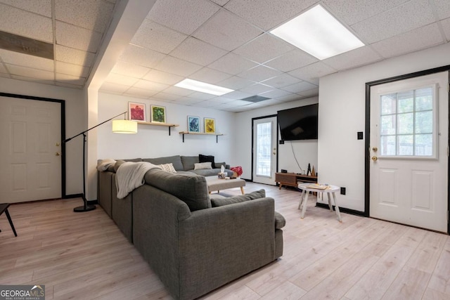 living room featuring a paneled ceiling and light hardwood / wood-style flooring