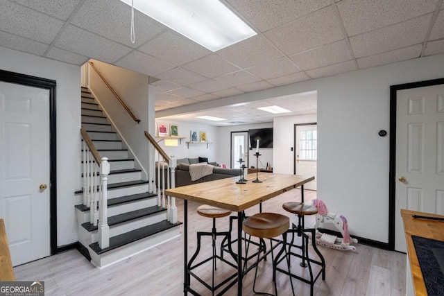 dining area with light hardwood / wood-style floors and a drop ceiling