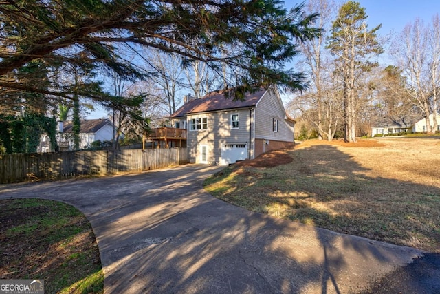 exterior space featuring a garage, a deck, and a lawn