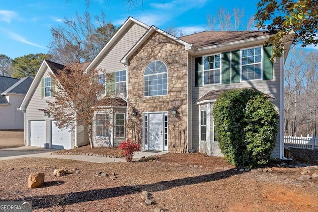 colonial house with stone siding, an attached garage, and concrete driveway