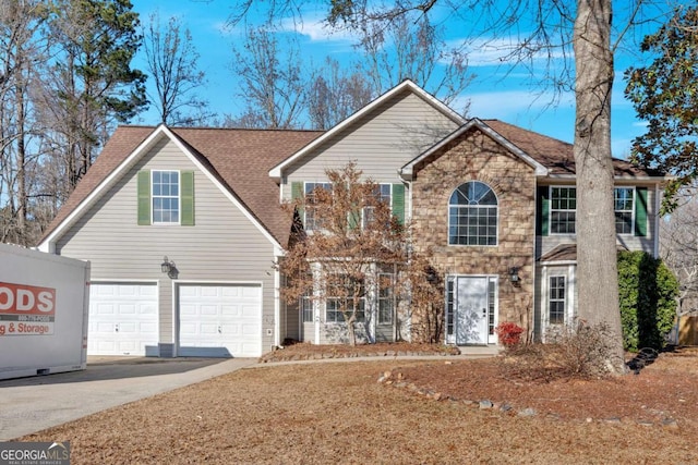 colonial house with concrete driveway, an attached garage, stone siding, and roof with shingles