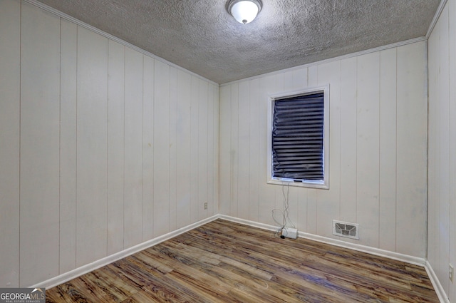 spare room featuring a textured ceiling, ornamental molding, and hardwood / wood-style flooring