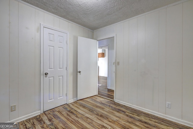 spare room with a textured ceiling, ornamental molding, and hardwood / wood-style flooring