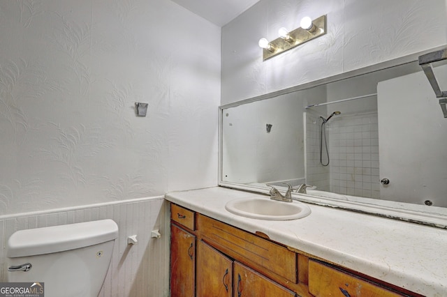 bathroom featuring vanity, a tile shower, and toilet