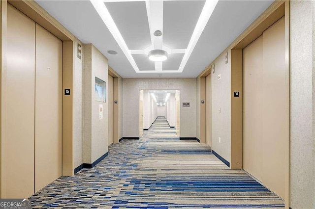 corridor with a tray ceiling and elevator