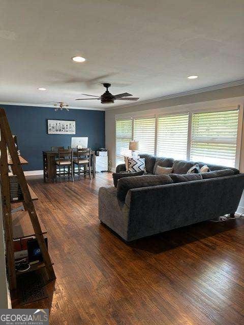 living room with crown molding, ceiling fan, and dark hardwood / wood-style floors